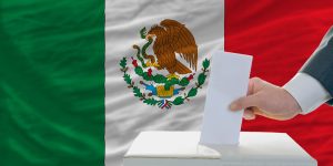 man voting on elections in mexico front of flag